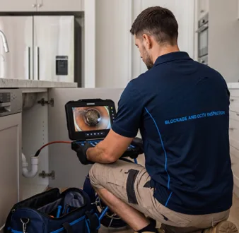 Plumber clearing a blocked toilet in a Revesby bathroom